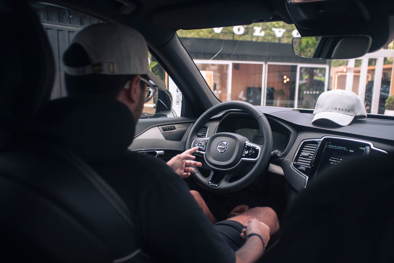 Wooden shelf with gray and olive drab green baseball caps, next to wooden clothes hanger with sweaters.